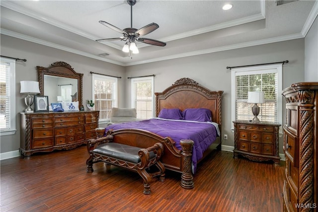 bedroom with crown molding, baseboards, a raised ceiling, and dark wood-type flooring