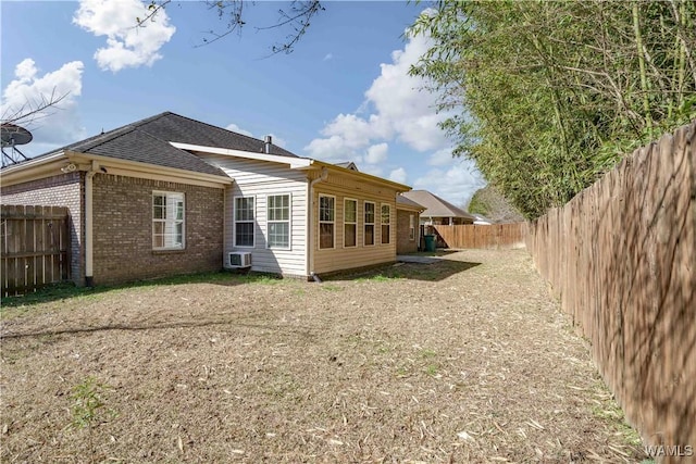 rear view of house featuring brick siding and a fenced backyard