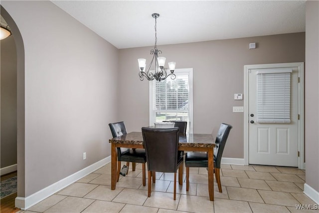 dining space featuring a chandelier, arched walkways, baseboards, and light tile patterned floors