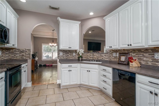 kitchen featuring dark countertops, white cabinetry, a sink, and black appliances