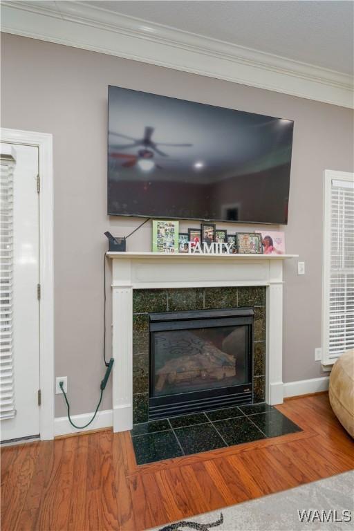 interior details with ornamental molding, a fireplace, baseboards, and wood finished floors