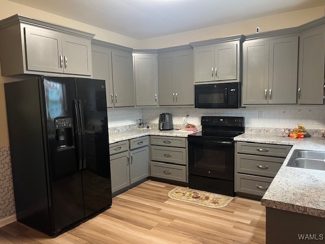 kitchen featuring gray cabinetry, black appliances, sink, light hardwood / wood-style flooring, and tasteful backsplash