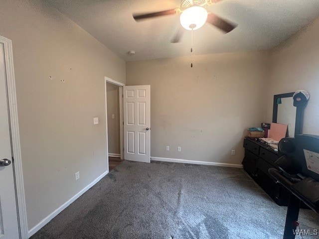 unfurnished bedroom with ceiling fan, dark carpet, and a textured ceiling