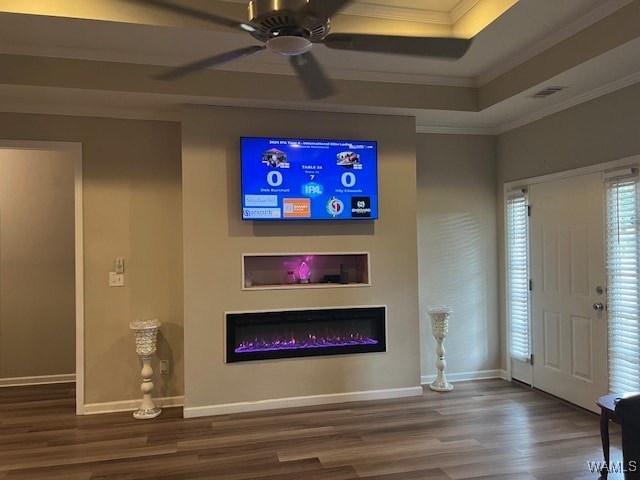 unfurnished living room featuring hardwood / wood-style flooring, ceiling fan, a raised ceiling, and ornamental molding