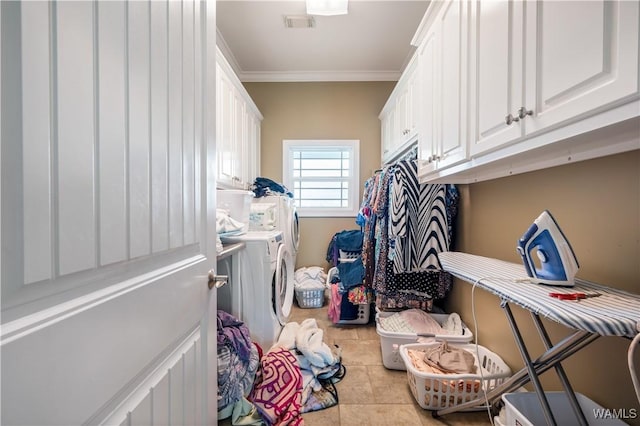 laundry room featuring washer and clothes dryer, cabinets, light tile patterned floors, and crown molding