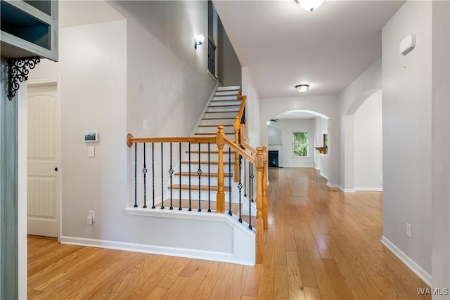 interior space featuring arched walkways, wood-type flooring, and baseboards