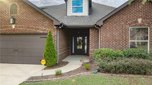 property entrance with an attached garage, brick siding, and a shingled roof