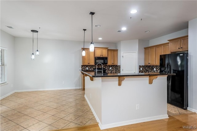 kitchen with a kitchen bar, dark countertops, black appliances, and tasteful backsplash