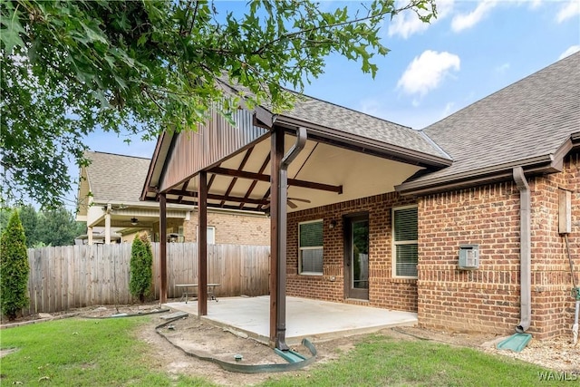 back of property with ceiling fan, brick siding, fence, and a patio