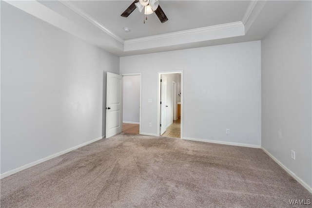 unfurnished bedroom with baseboards, a tray ceiling, crown molding, and light colored carpet