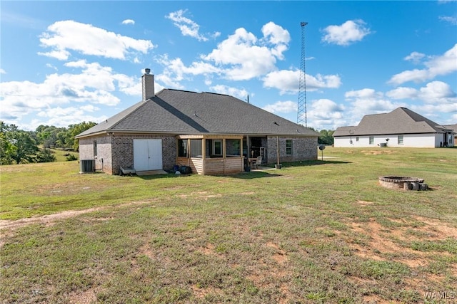 back of property with a fire pit, central AC unit, and a yard