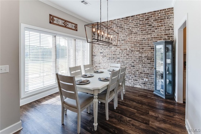 dining area with brick wall, dark hardwood / wood-style flooring, a notable chandelier, and crown molding