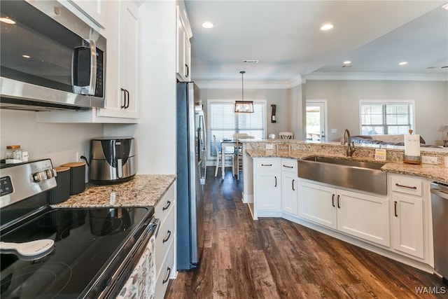 kitchen featuring stainless steel appliances, white cabinets, pendant lighting, and sink