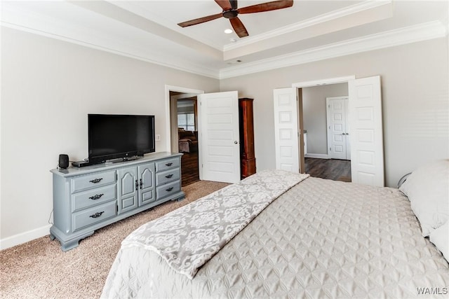 carpeted bedroom featuring ceiling fan, crown molding, and a tray ceiling