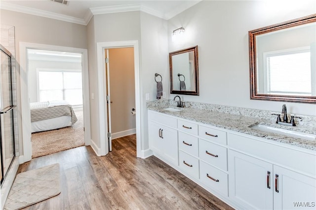 bathroom with vanity, a shower with shower door, hardwood / wood-style flooring, and crown molding