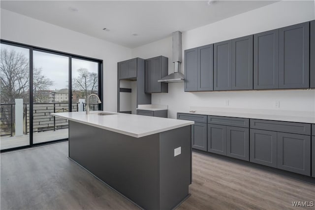 kitchen featuring sink, a center island with sink, gray cabinets, and hardwood / wood-style flooring