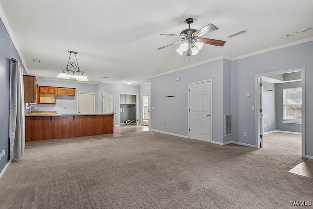 unfurnished living room featuring ceiling fan, light colored carpet, ornamental molding, and sink