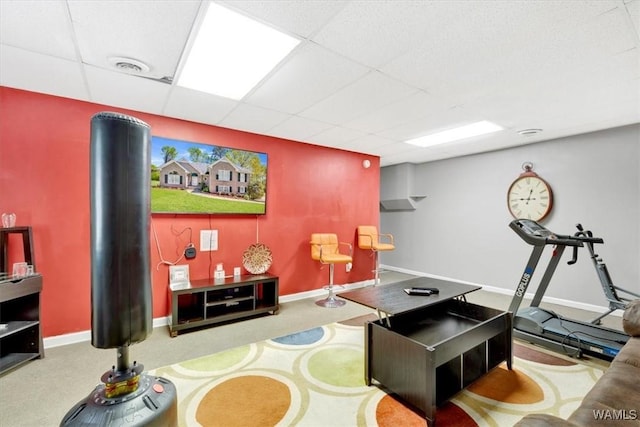 interior space with a paneled ceiling and light carpet