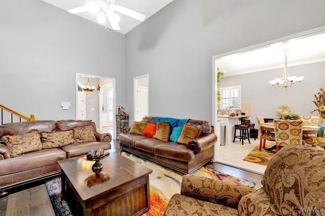 living room featuring a towering ceiling, ceiling fan with notable chandelier, and hardwood / wood-style floors