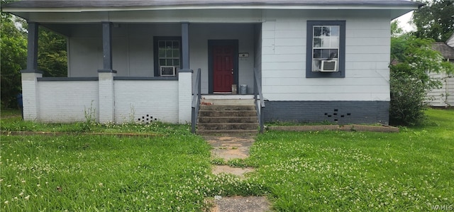 view of front of property featuring cooling unit, covered porch, and a front lawn