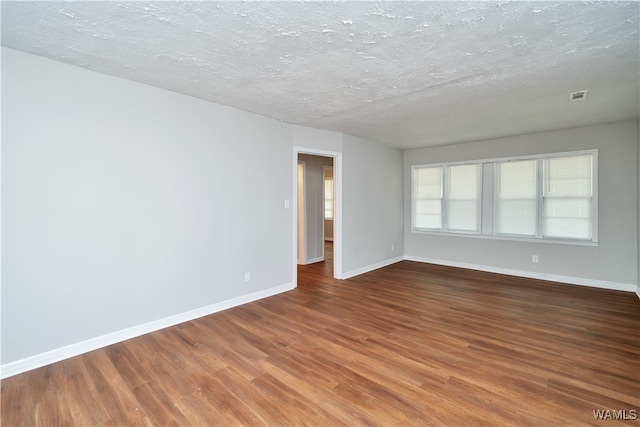 empty room featuring wood-type flooring and a textured ceiling