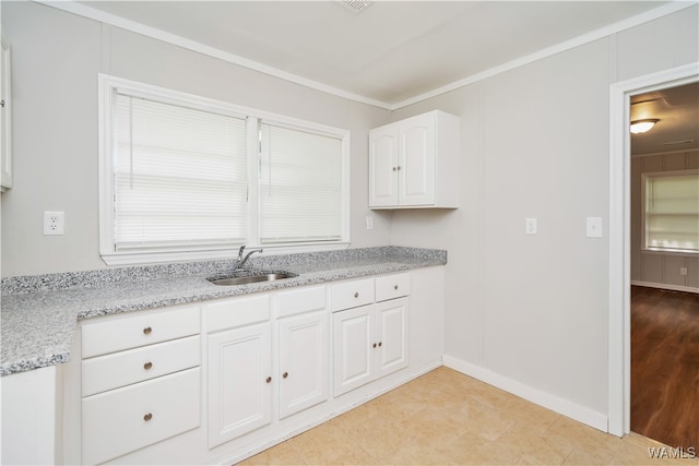 kitchen featuring light stone countertops, sink, light wood-type flooring, white cabinets, and ornamental molding