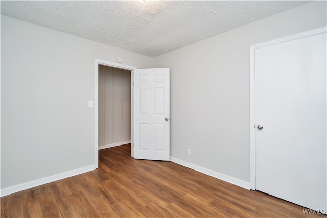 empty room with a textured ceiling and dark wood-type flooring