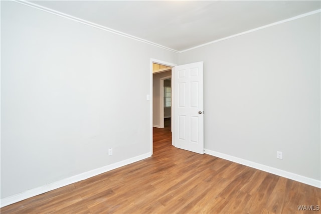 empty room featuring wood-type flooring and crown molding