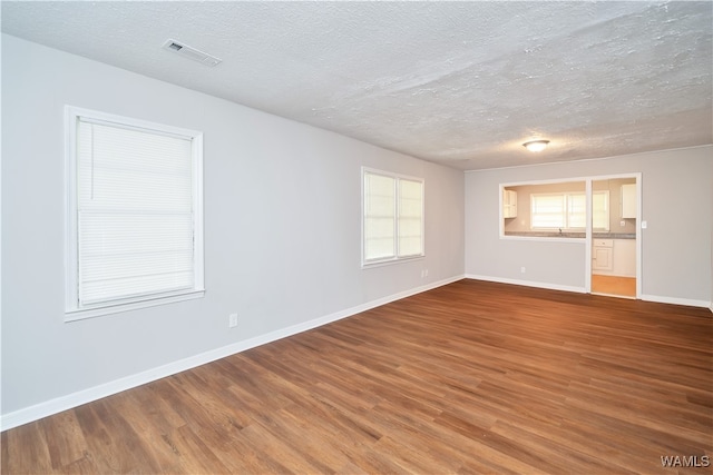 unfurnished room with wood-type flooring and a textured ceiling