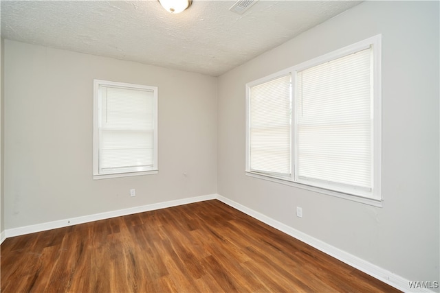 spare room with dark hardwood / wood-style flooring and a textured ceiling