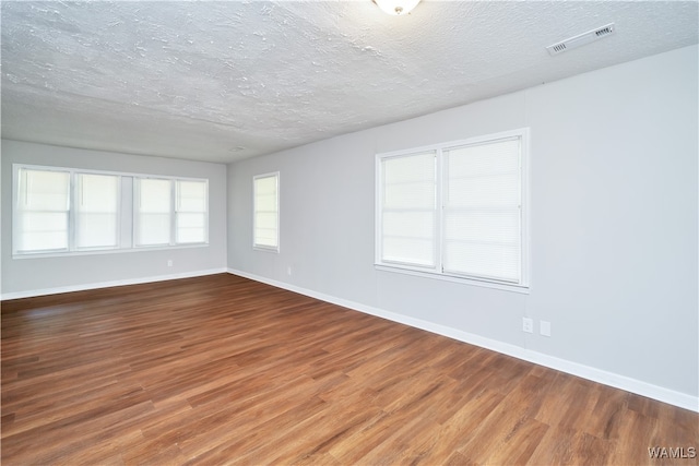 empty room with wood-type flooring and a textured ceiling