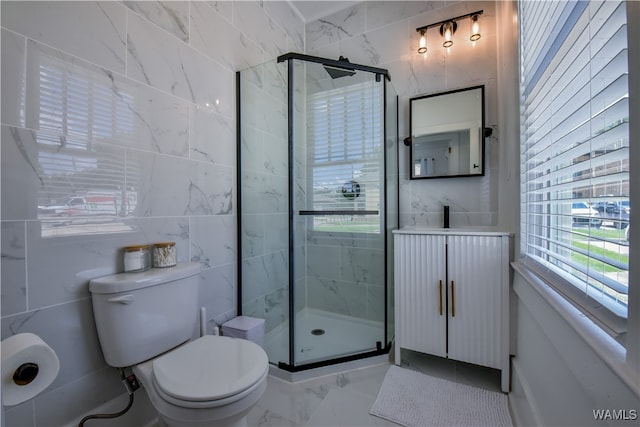 bathroom featuring vanity, a shower with door, toilet, and tile walls