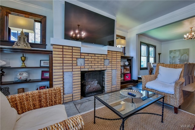 living room with a notable chandelier, a fireplace, light wood-type flooring, and crown molding