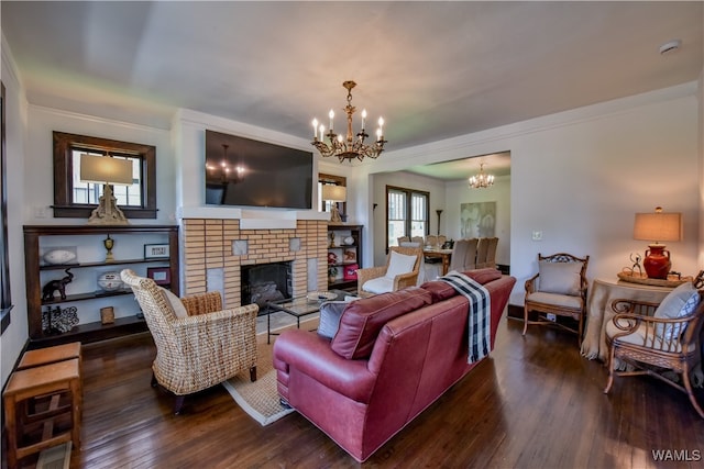 living room with crown molding, a brick fireplace, dark wood-type flooring, and a notable chandelier