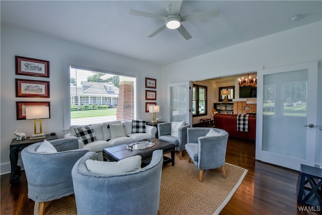 living room with dark wood-type flooring and ceiling fan with notable chandelier