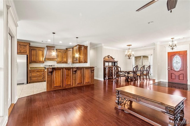 kitchen featuring dark hardwood / wood-style flooring, ornamental molding, custom range hood, pendant lighting, and white refrigerator