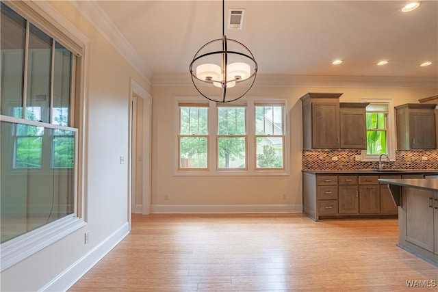 890 Founders St, Tuscaloosa, AL 35406 - kitchen featuring decorative backsplash, dark countertops, light wood-style flooring, crown molding, and hanging light fixtures
