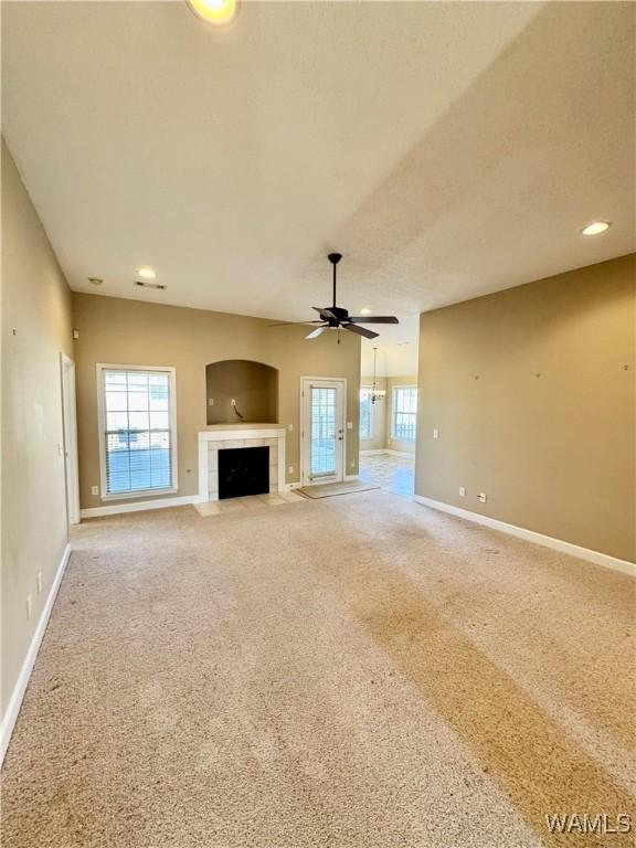 unfurnished living room with ceiling fan, a tile fireplace, and carpet floors