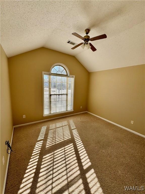 carpeted spare room with lofted ceiling, ceiling fan, and a textured ceiling