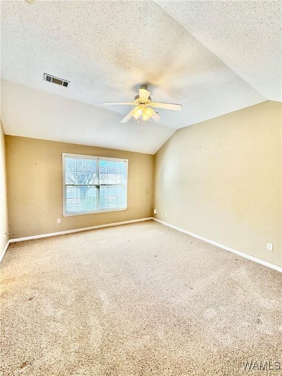 carpeted empty room featuring ceiling fan, a textured ceiling, and vaulted ceiling