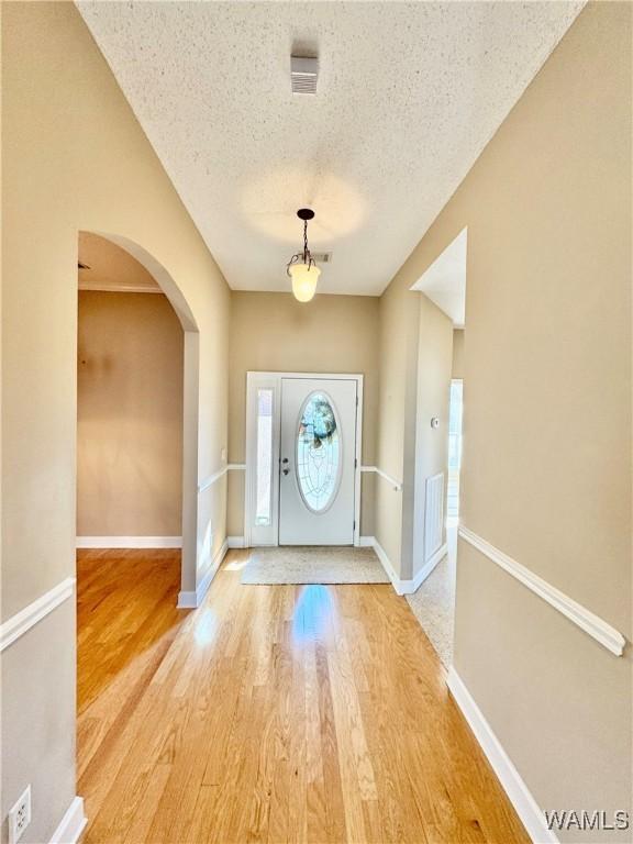 doorway with a wealth of natural light, a textured ceiling, and hardwood / wood-style flooring