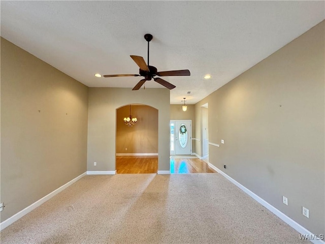 unfurnished room featuring light colored carpet and ceiling fan with notable chandelier