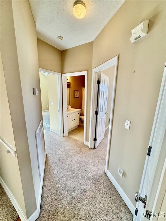 corridor featuring light carpet and a textured ceiling