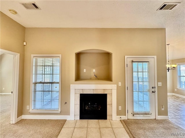 unfurnished living room featuring plenty of natural light, light tile patterned floors, a tile fireplace, and a chandelier