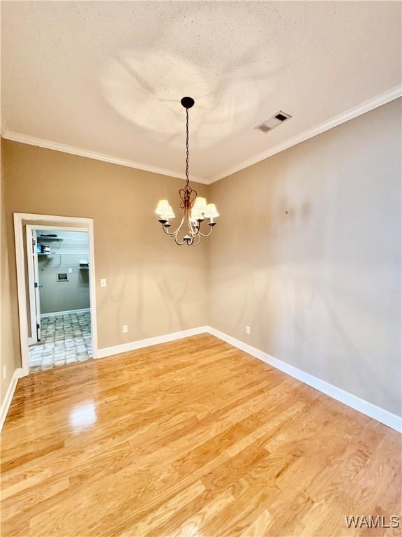 unfurnished dining area featuring a textured ceiling, hardwood / wood-style floors, crown molding, and an inviting chandelier