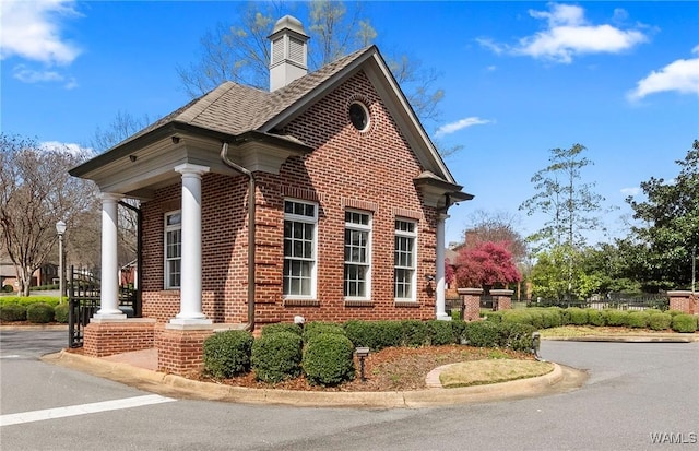 view of property exterior with a shingled roof, a chimney, fence, and brick siding