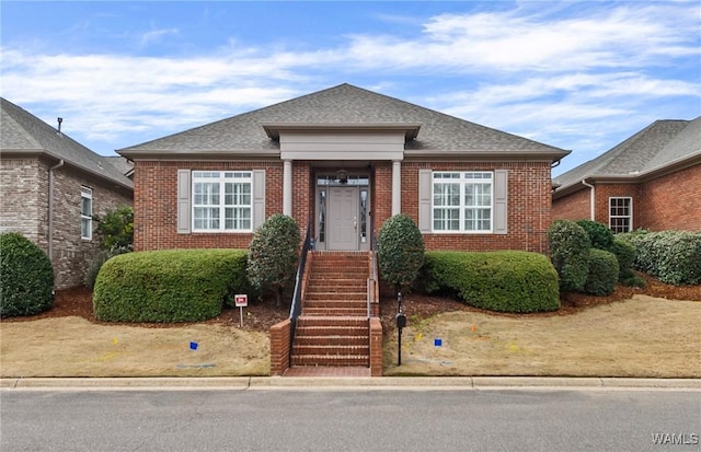 bungalow-style home with a shingled roof and brick siding