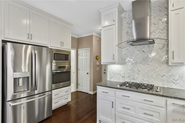 kitchen featuring tasteful backsplash, dark stone counters, wall chimney exhaust hood, appliances with stainless steel finishes, and crown molding