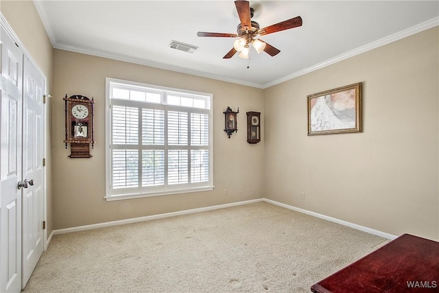 carpeted spare room with a ceiling fan, baseboards, visible vents, and crown molding