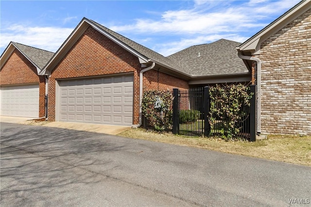 view of front of property with a garage, brick siding, roof with shingles, and fence